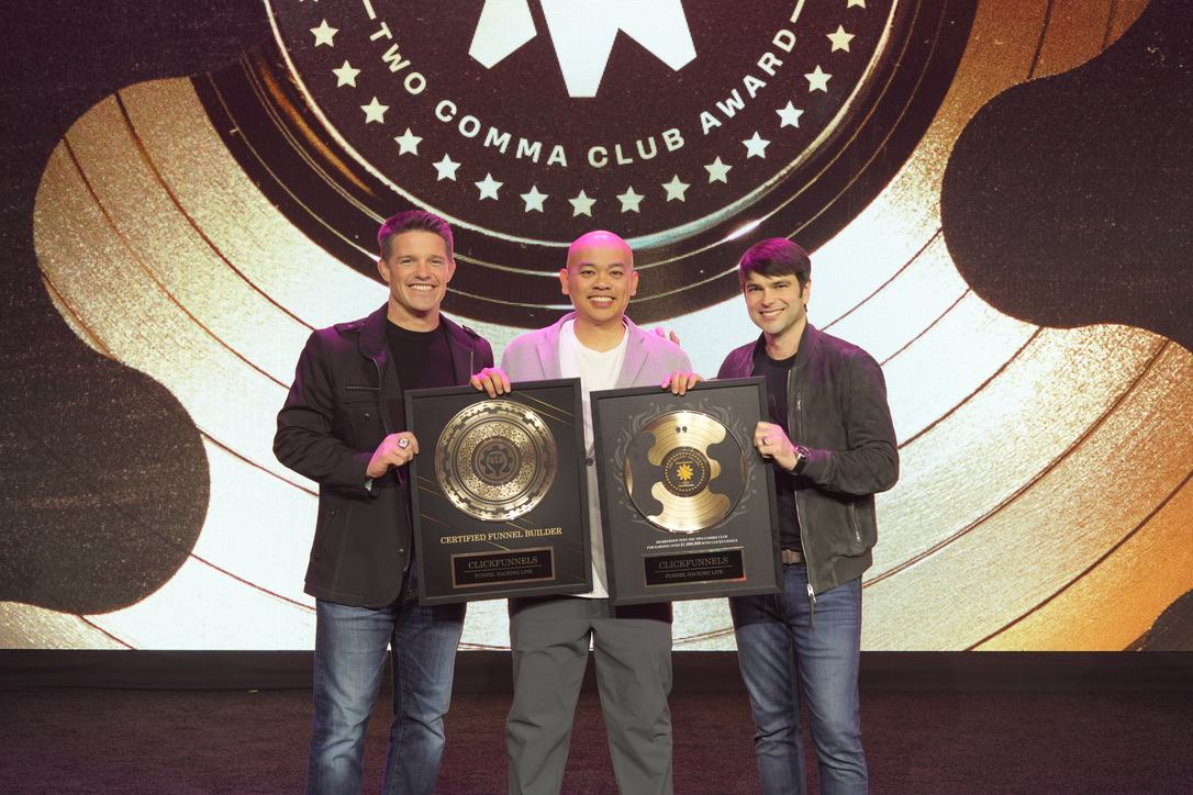 Two Comma Club 颁奖台上，卢卡斯 Lucas 与 ClickFunnels 两位创办人手持奖座